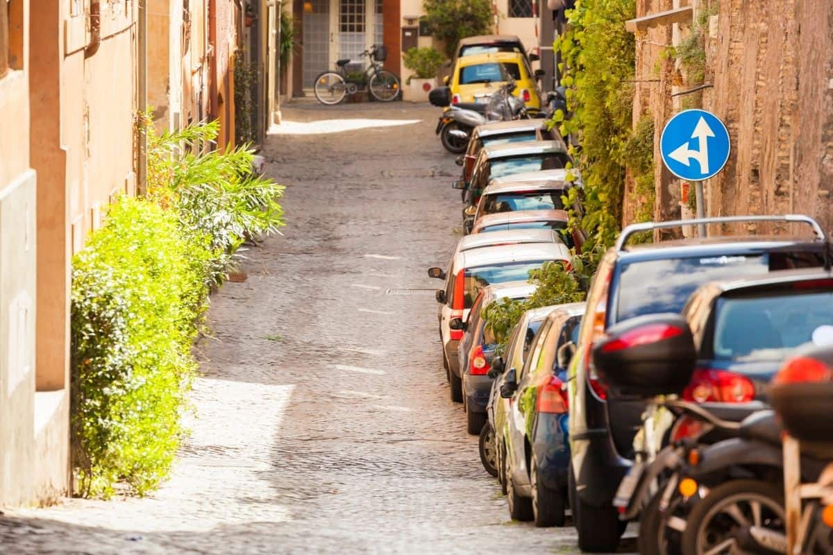 A narrow European street lined with parked cars