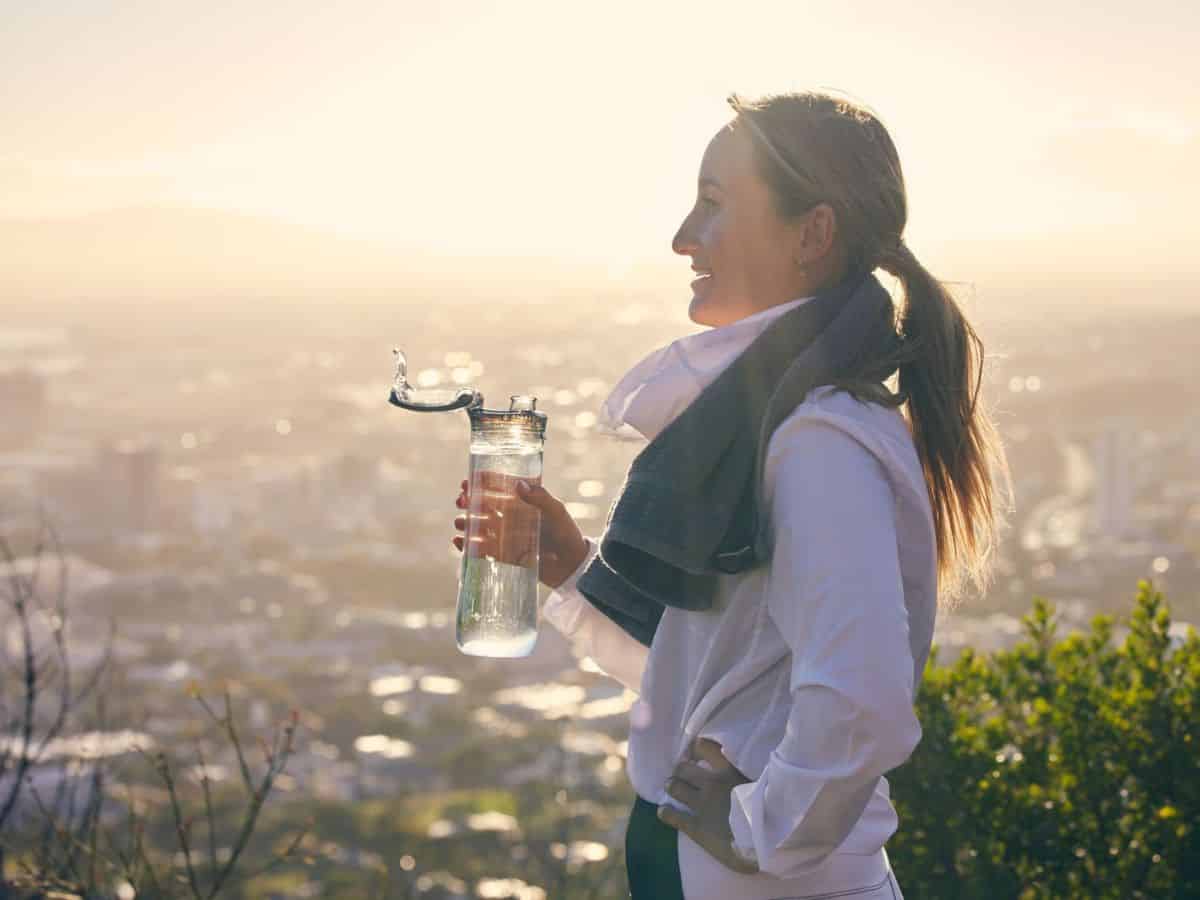 A woman holding a water bottle in front of a city.