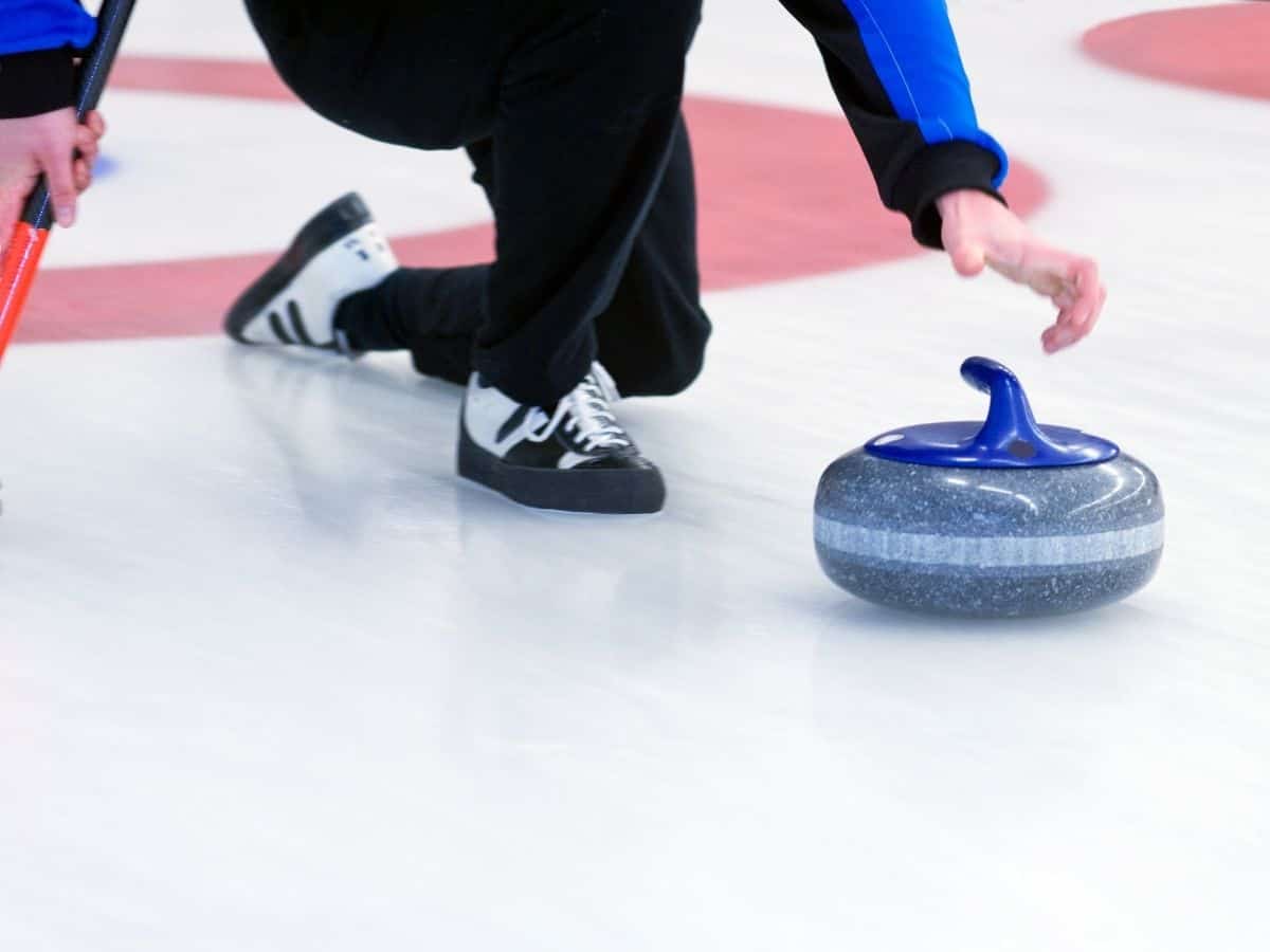 Person sliding a curling stone across the ice