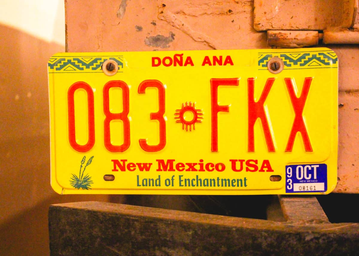Red and gold New Mexico license plate with a Zia symbol