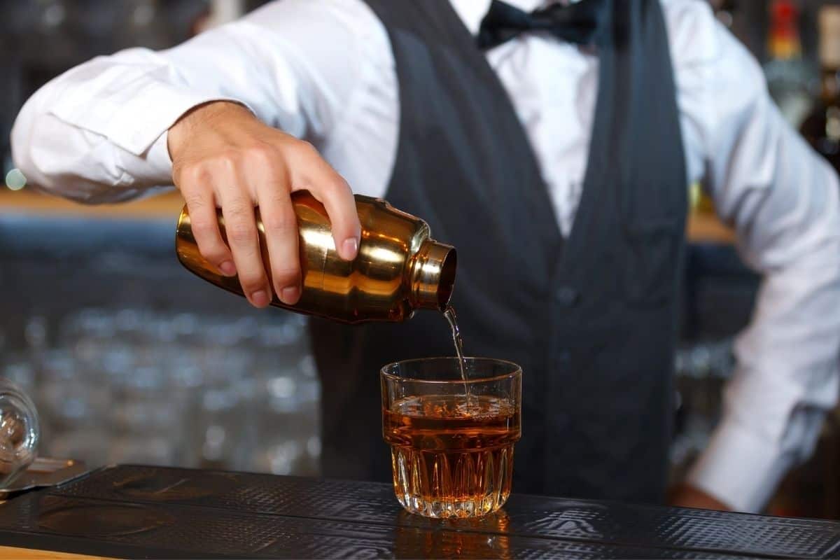 A man in a vest pouring a cocktail