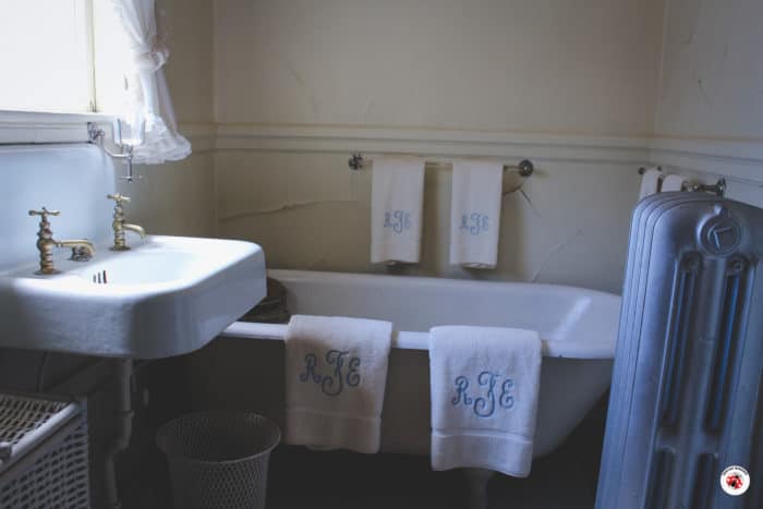 A 20th century bathtub with embroidered towels hanging over the edge.