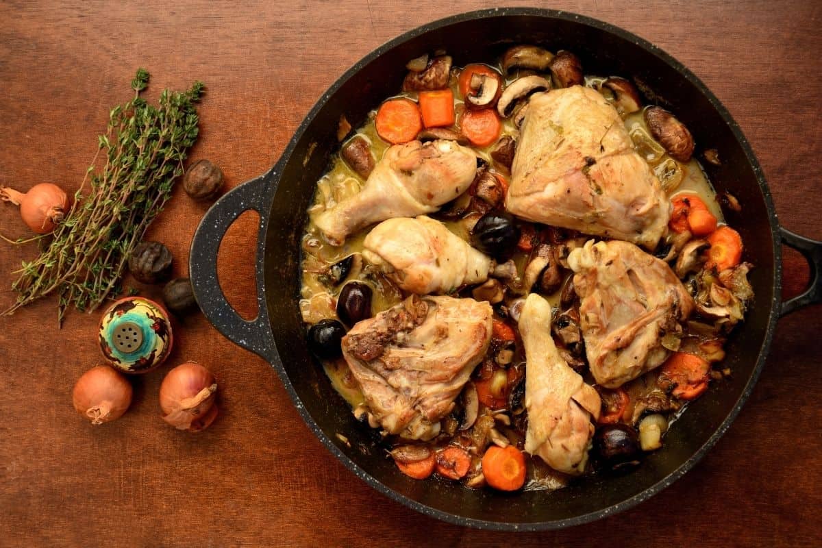 A steaming bowl of coq au vin with chicken breasts and white wine sauce