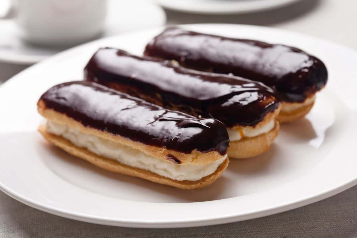 Three chocolate topped eclairs on a white plate