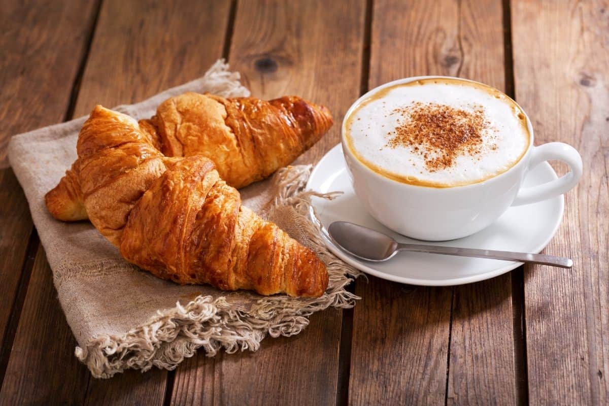 Two croissants with a latte on a wooden table