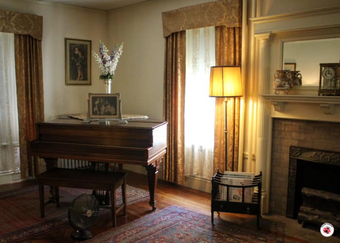 A formal sitting room with a piano and lamp at the FJK Birthplace.