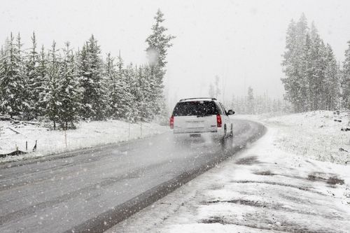 White Suburban driving down snowy road