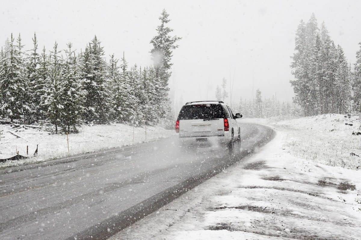 A white SUV driving on a snowy road