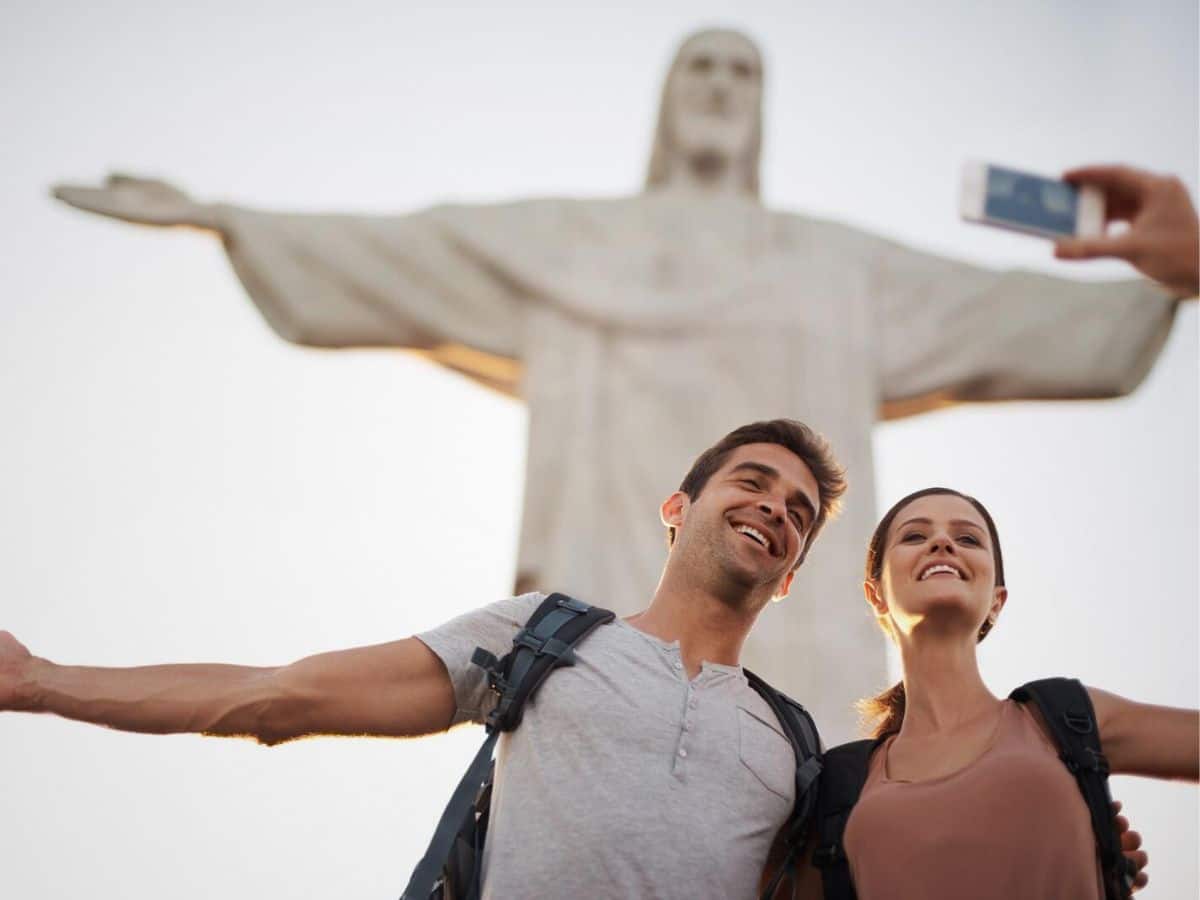 A couple completing a scavenger hunt takes a selfie in front of the Christ the Redeemer statue in Rio de Janeiro.
