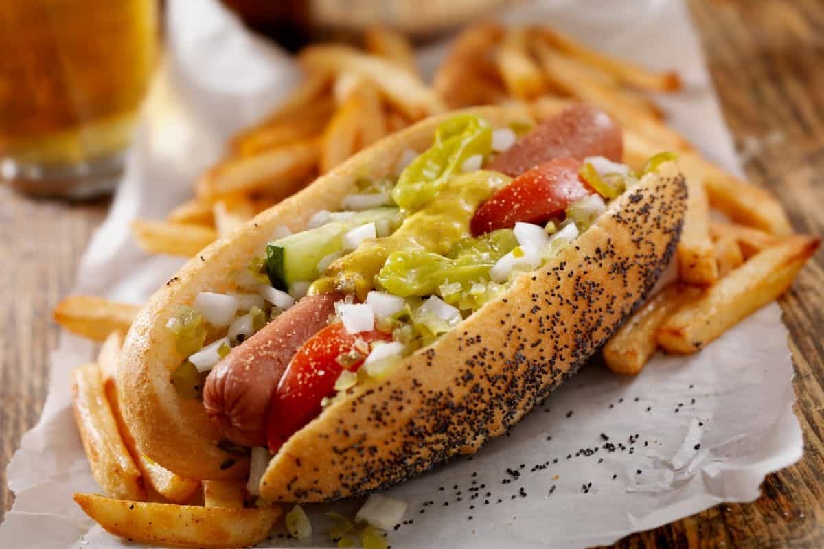 A Chicago-style hot dog with French fries and a beer