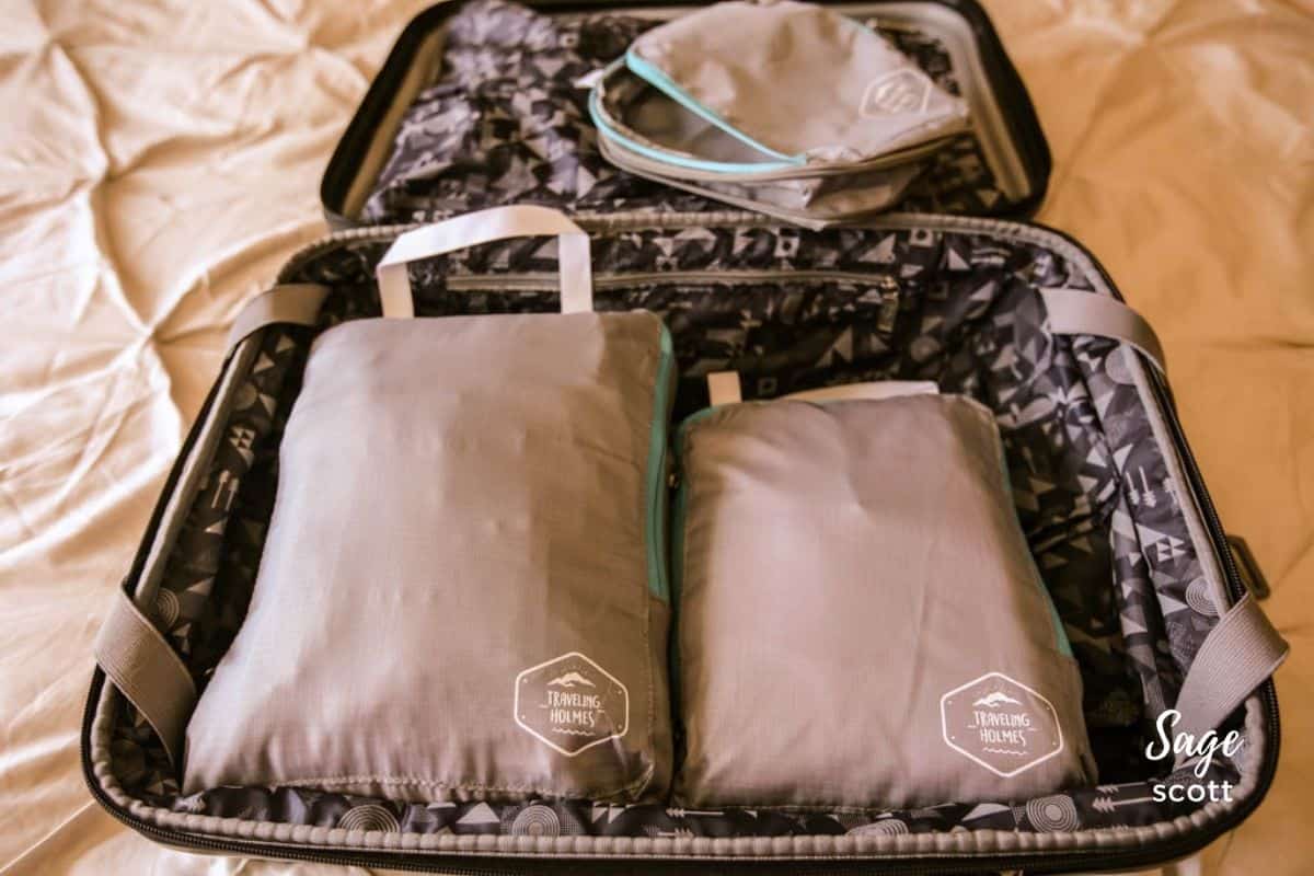 A suitcase packed with three grey compression packing cubes