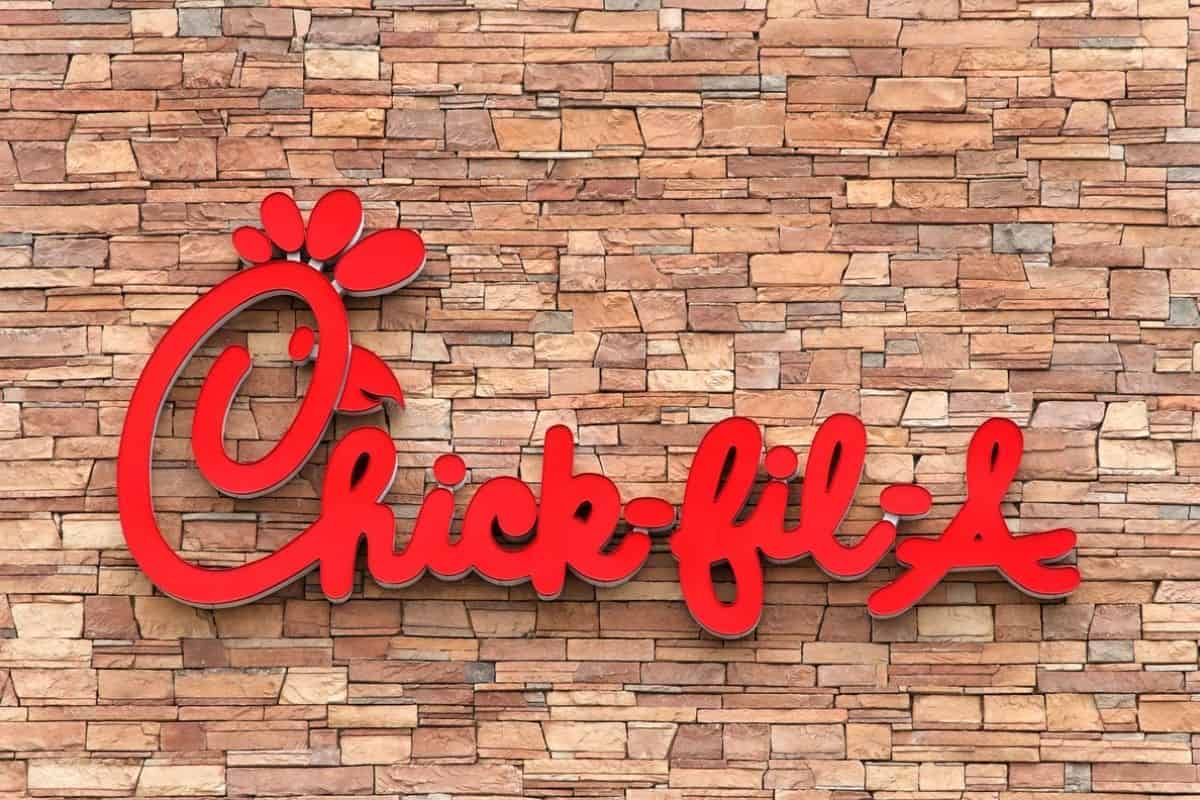 The red Chick-fil-A logo against a brown brick wall