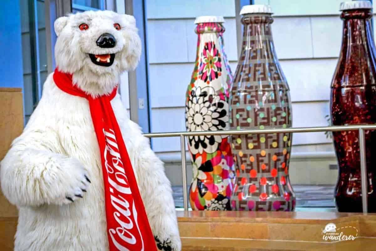 The Coca-Cola polar bear stands by decorated Coke bottles inside the World of Coca-Cola