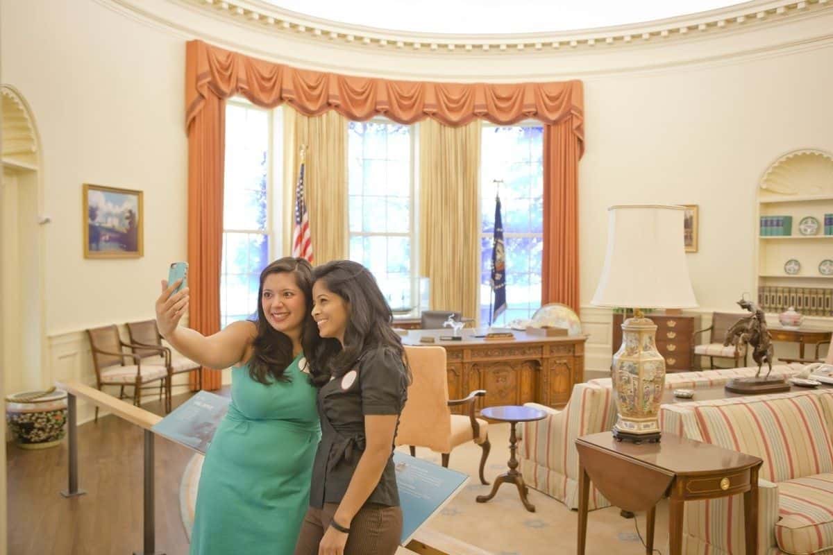 Two women pose in front of a replica of the Oval Office at the Carter Museum in Atlanta