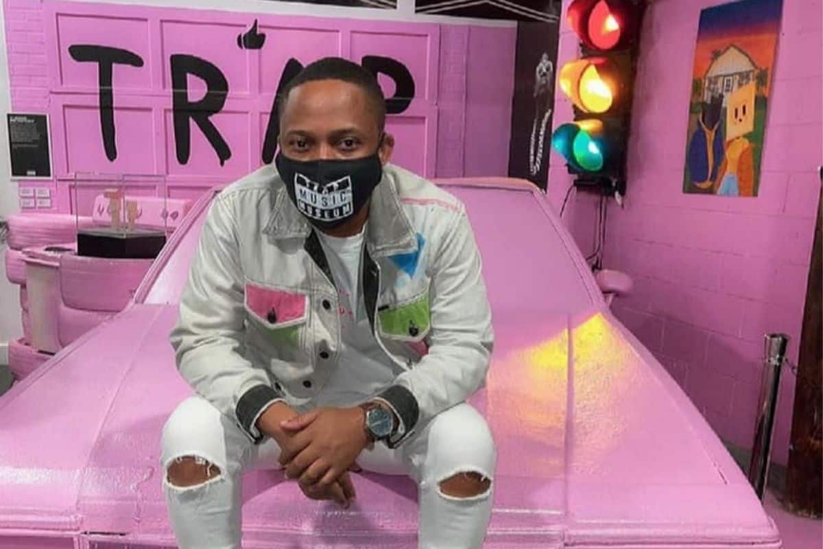 Man sitting on the hood of a pink car on display at trap Music Museum in Atlanta