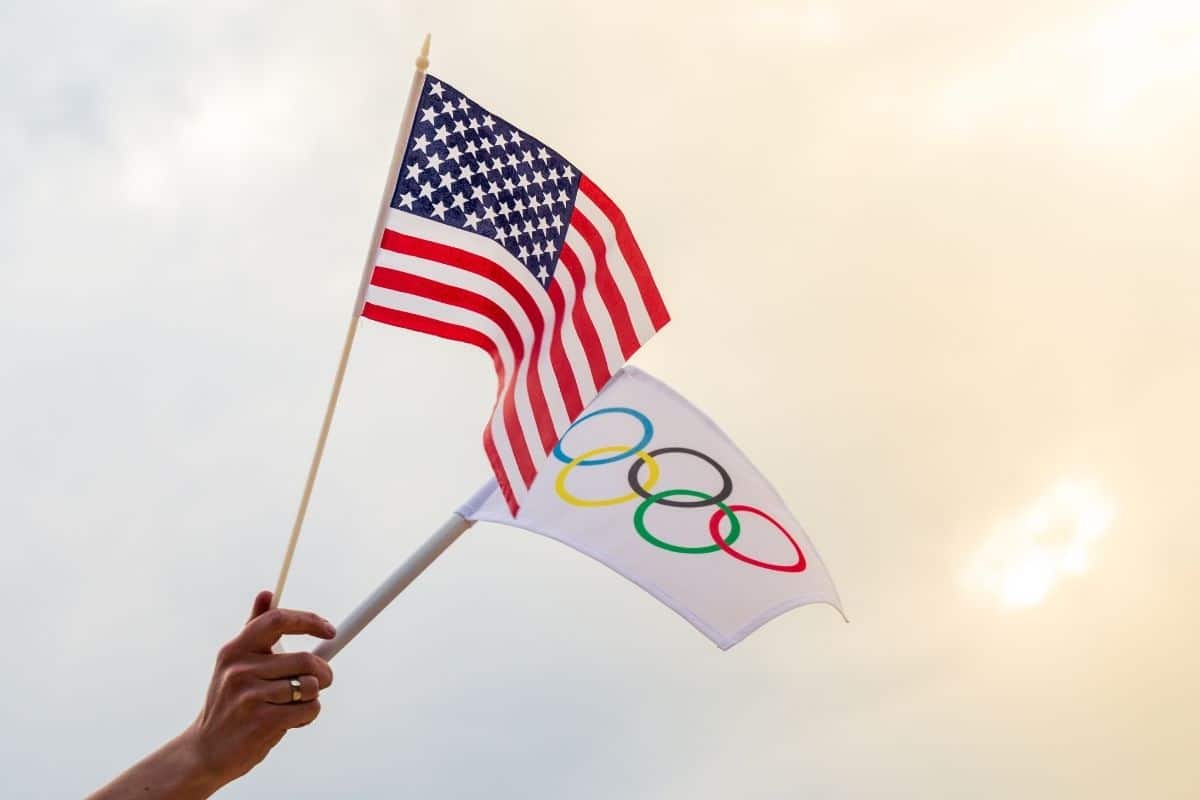 A hand holding the Team USA and Olympic flags