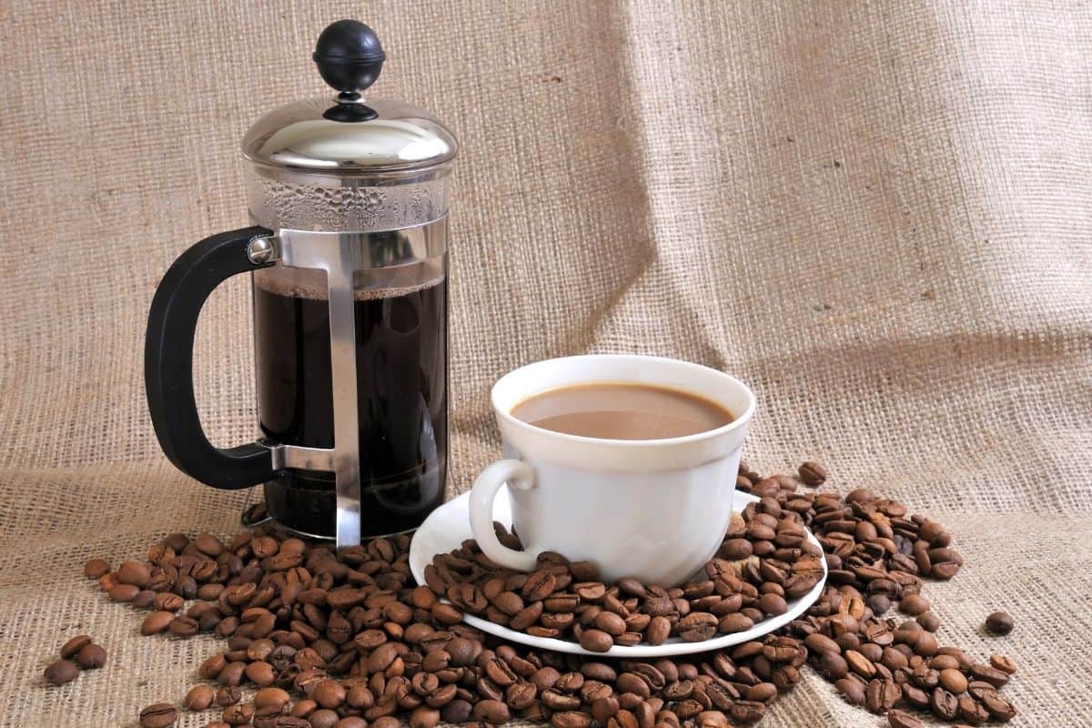 French press with cup of coffee and coffee beans