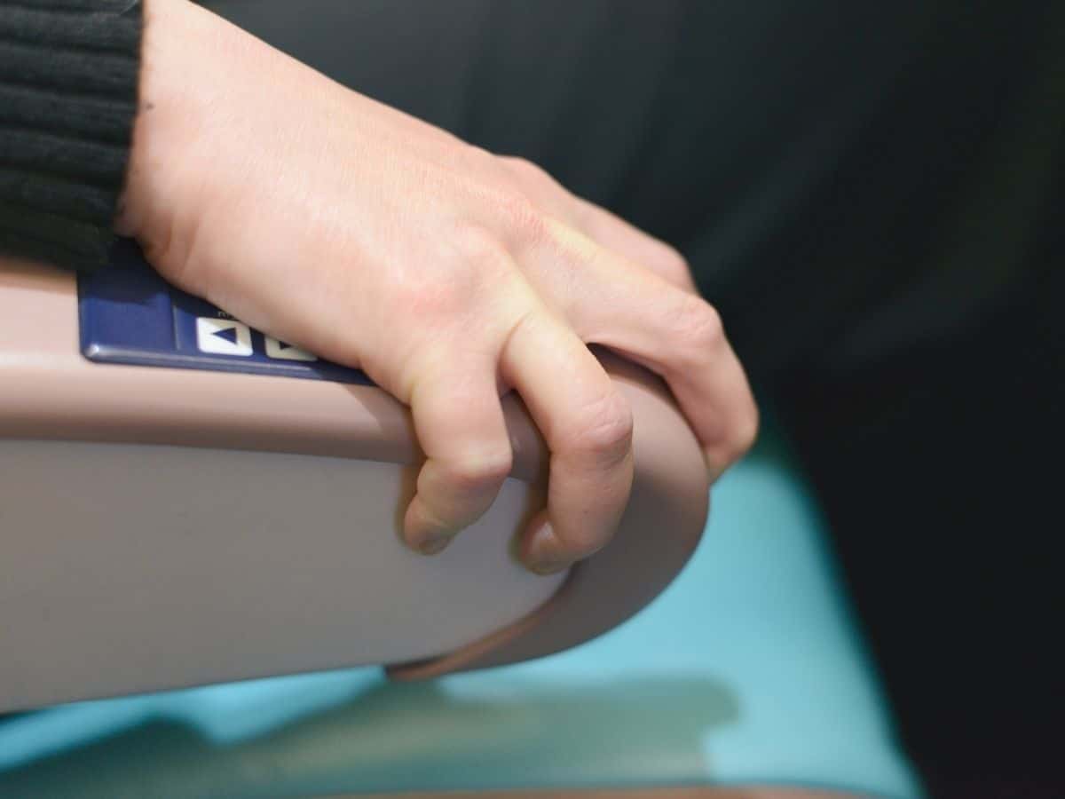 Person gripping arm rest on plane