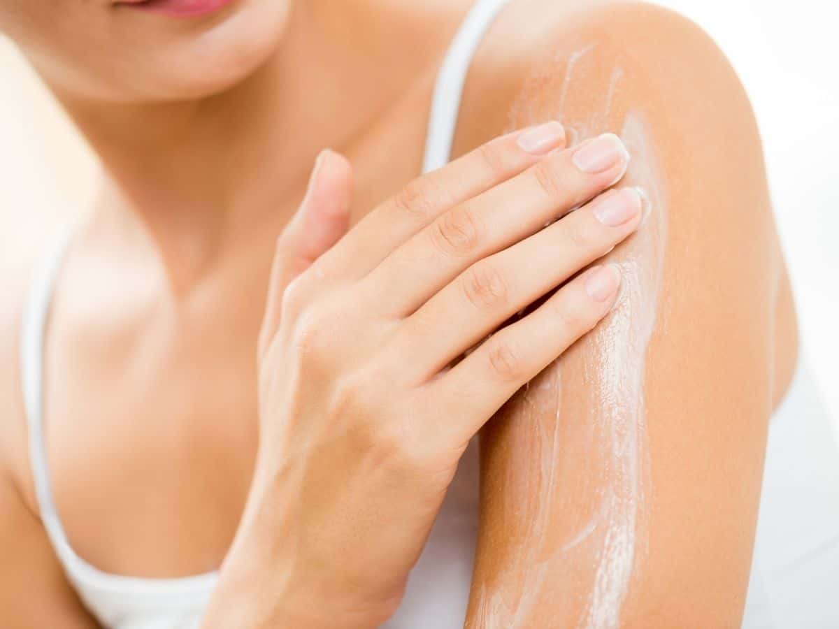 Woman rubbing lotion on her arm