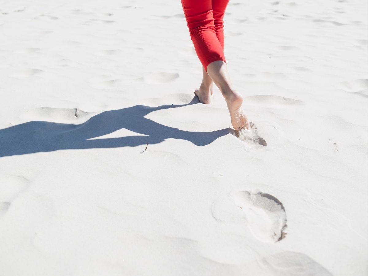 Woman in red pants running through white sand