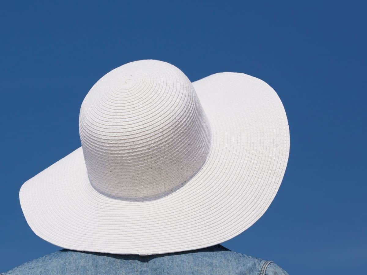 A wide-brimmed white sun hat against a clear blue sky background