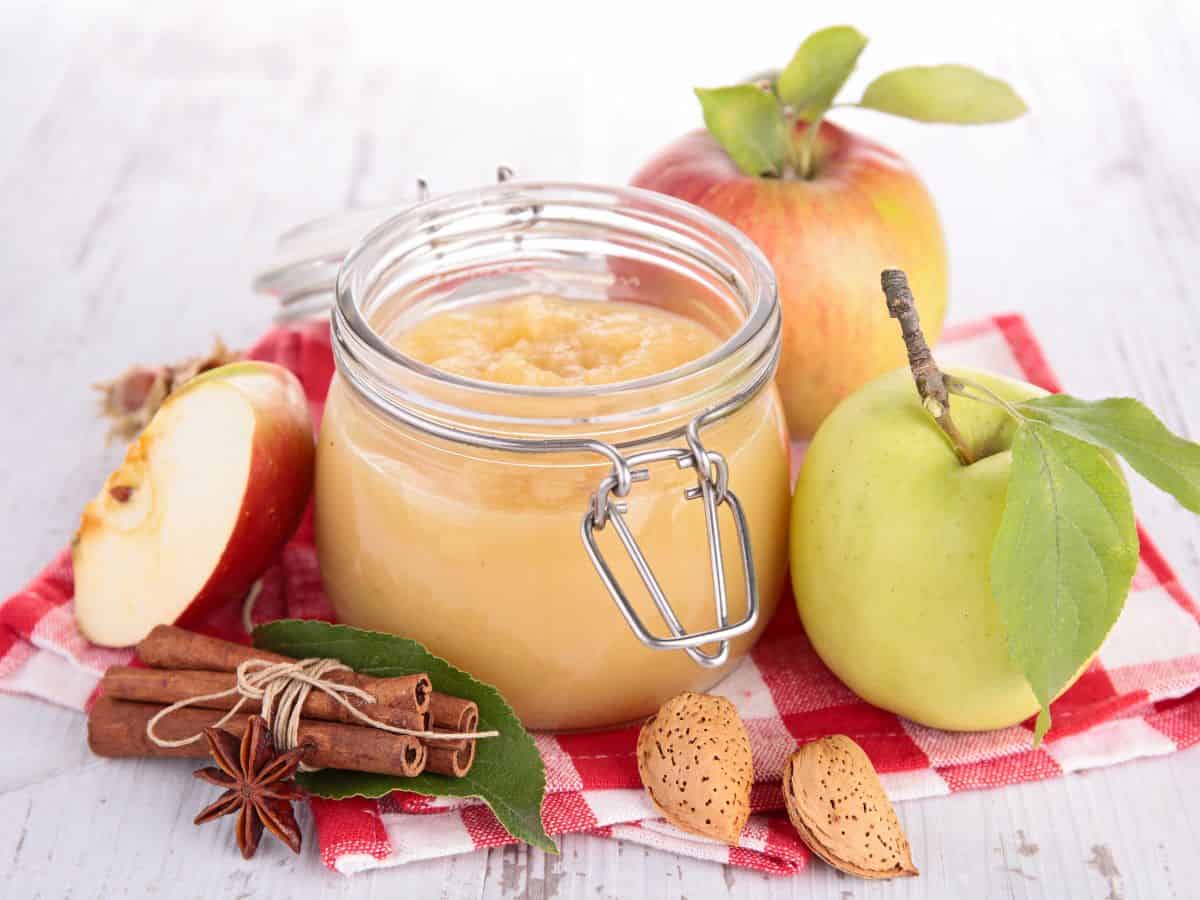 Jar of Homemade Applesauce Surrounded by Apples