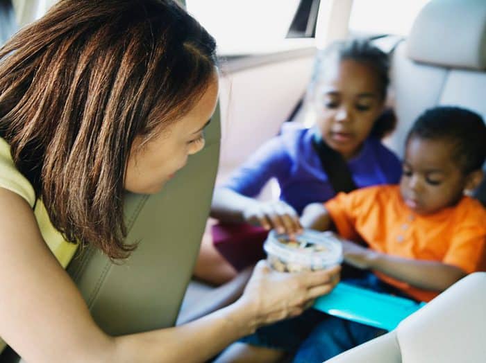 Mom Handing Container of Snacks to Kids in Back Seat