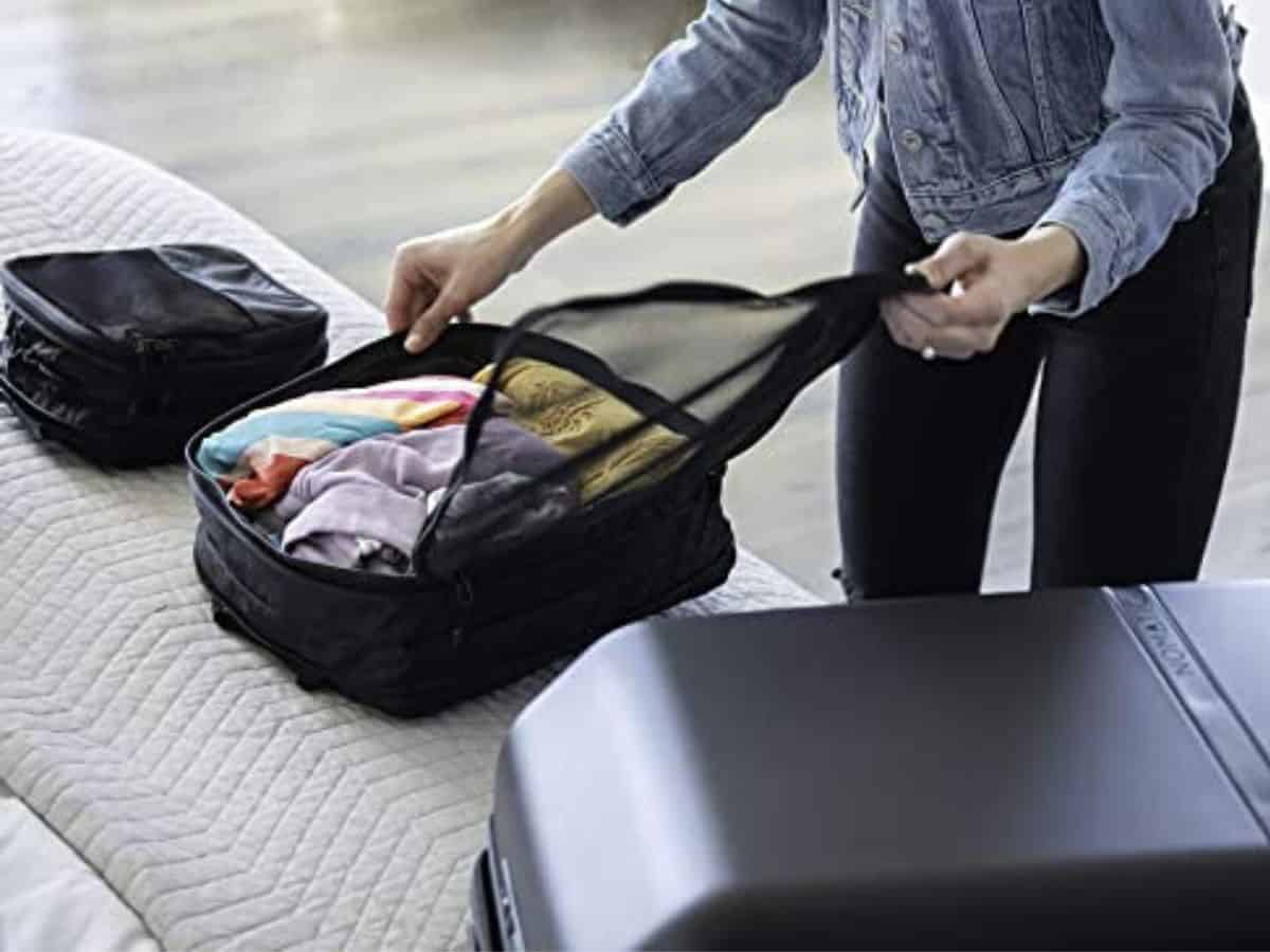 Woman packing compression cubes into suitcase.