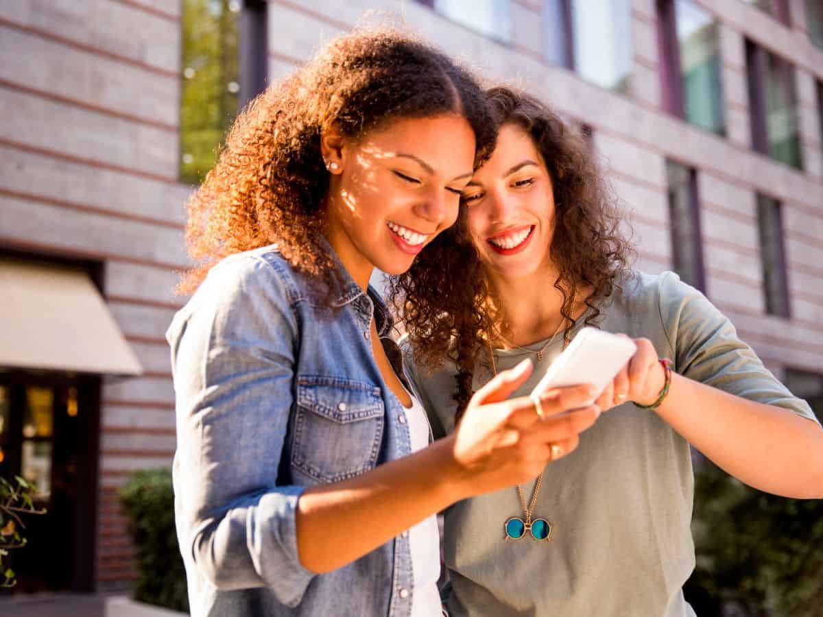 Two women looking at phone screen on a digital scavenger hunt