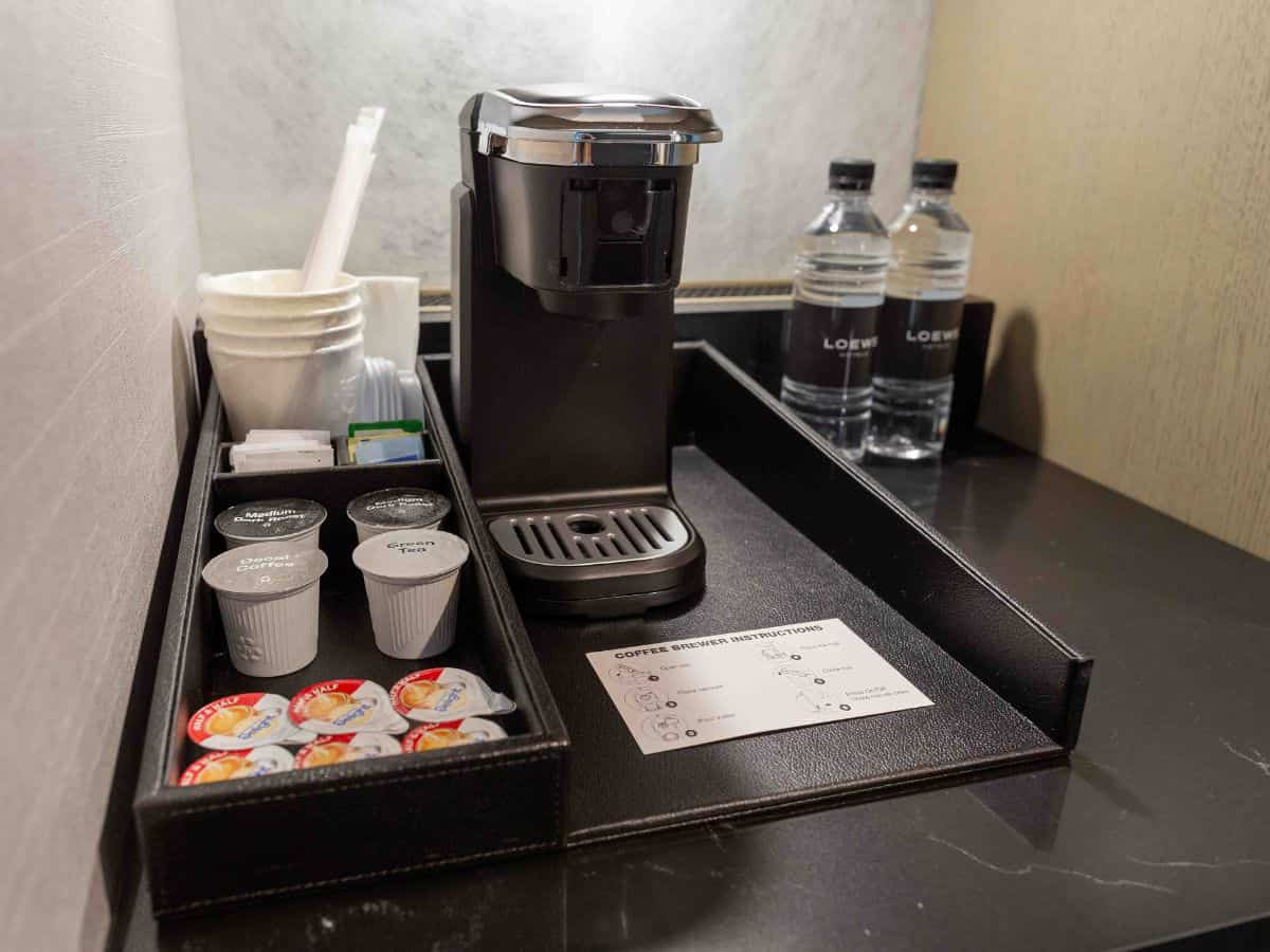 A coffee maker and a cup of coffee in a Loews Kansas City hotel room.