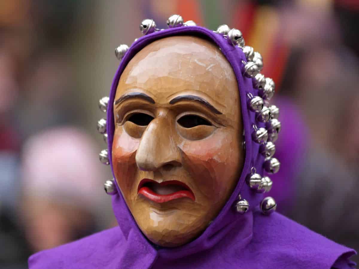 A person wearing a purple mask in a Carnival parade in Germany.