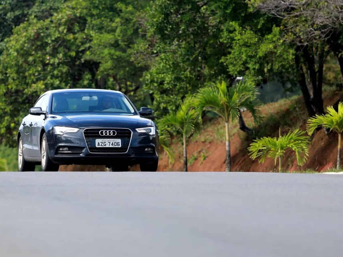 A black Audi, one of Germany's famous automobile brands, gracefully glides down a picturesque country road.