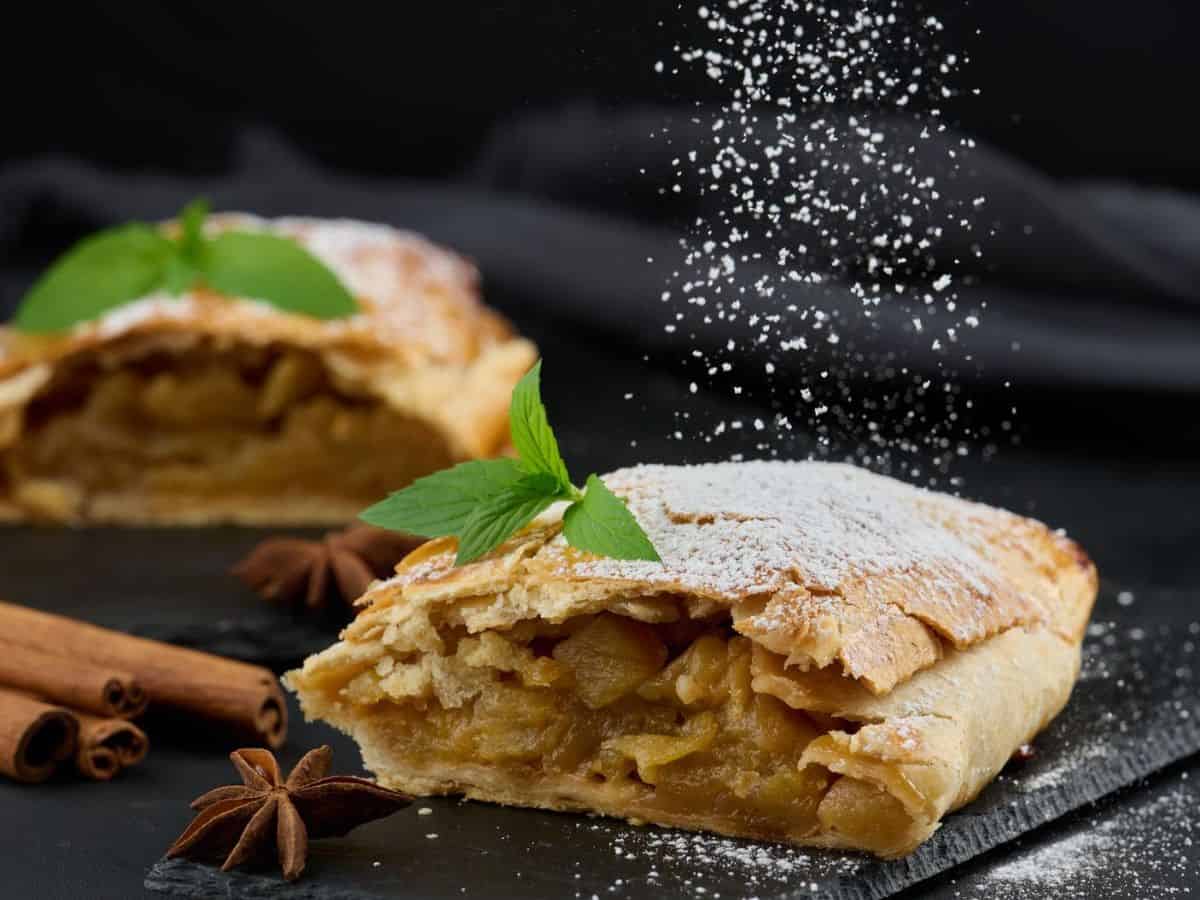 Apple pastry with powdered sugar and cinnamon on a dark background, showcasing the delicious flavors of Germany.