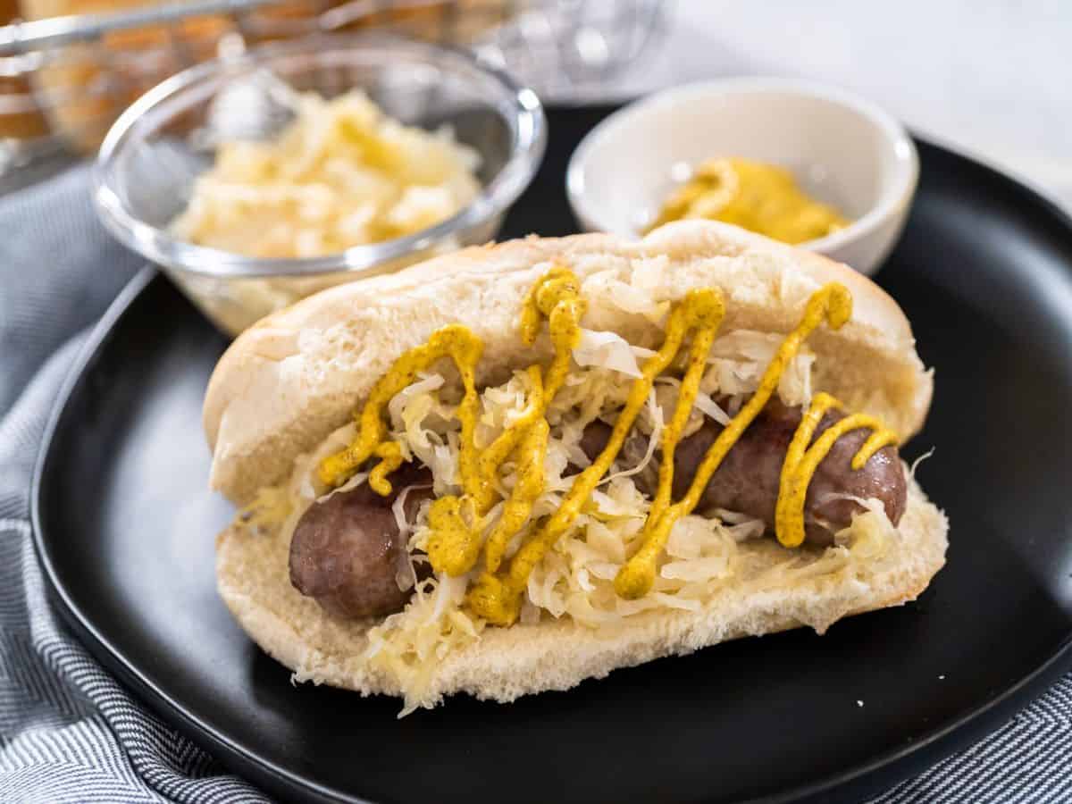 Bratwurst with sauerkraut on a black plate, paying homage to Germany's culinary traditions.