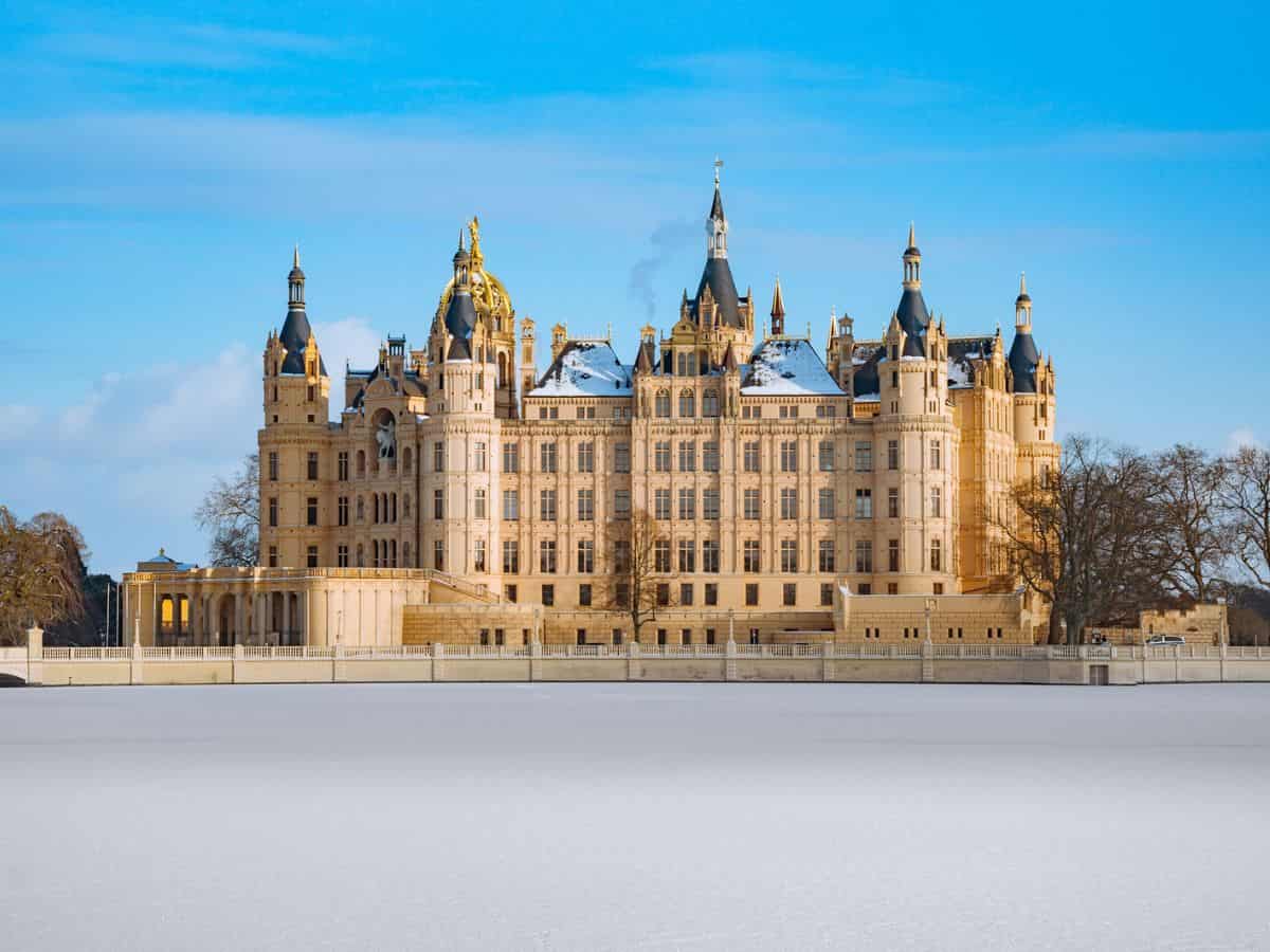A large German castle sitting on top of a snowy field.