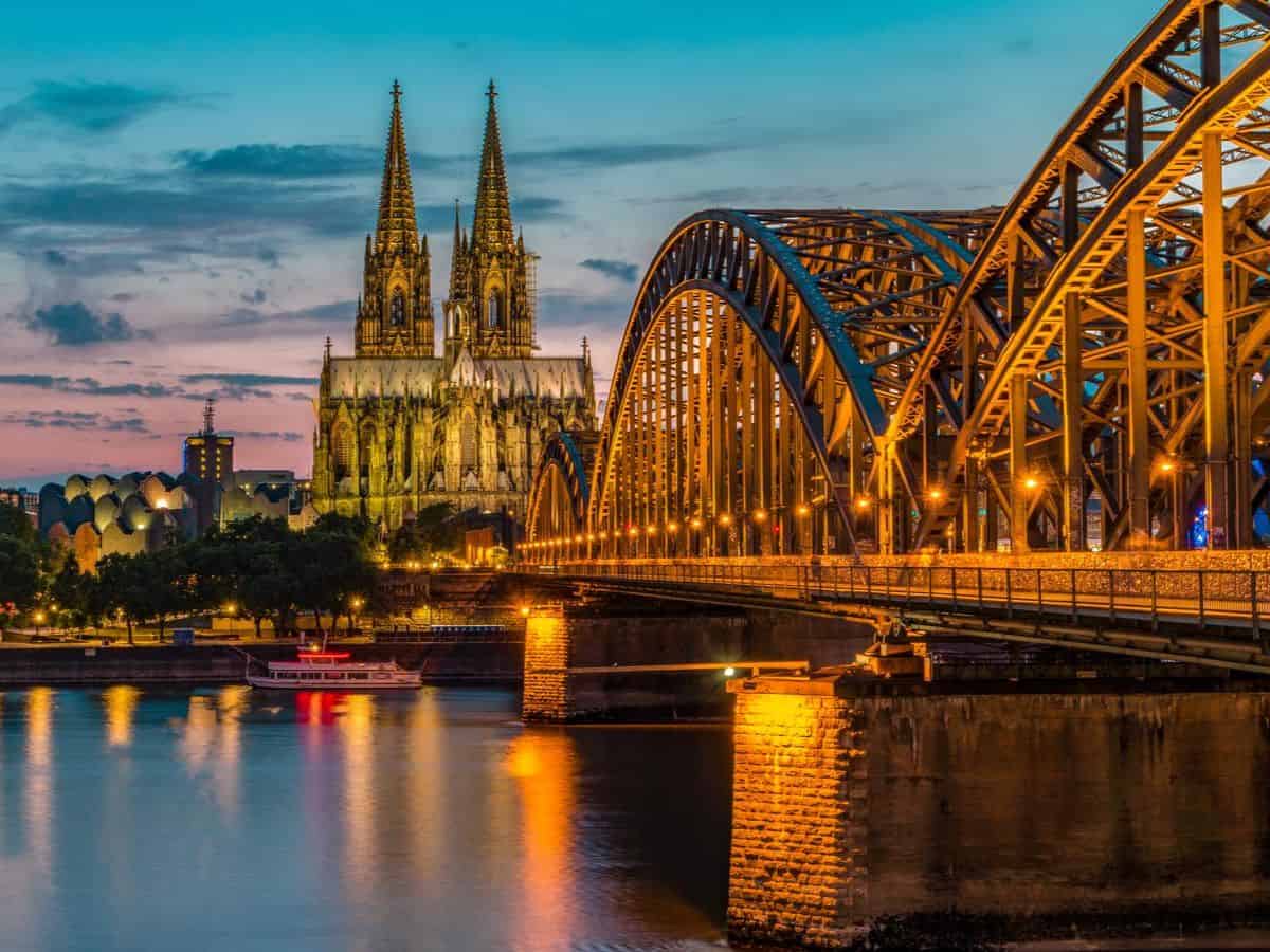 The Cologne Cathedral, a famous landmark in Germany, stands majestically along the picturesque Rhine River at dusk.