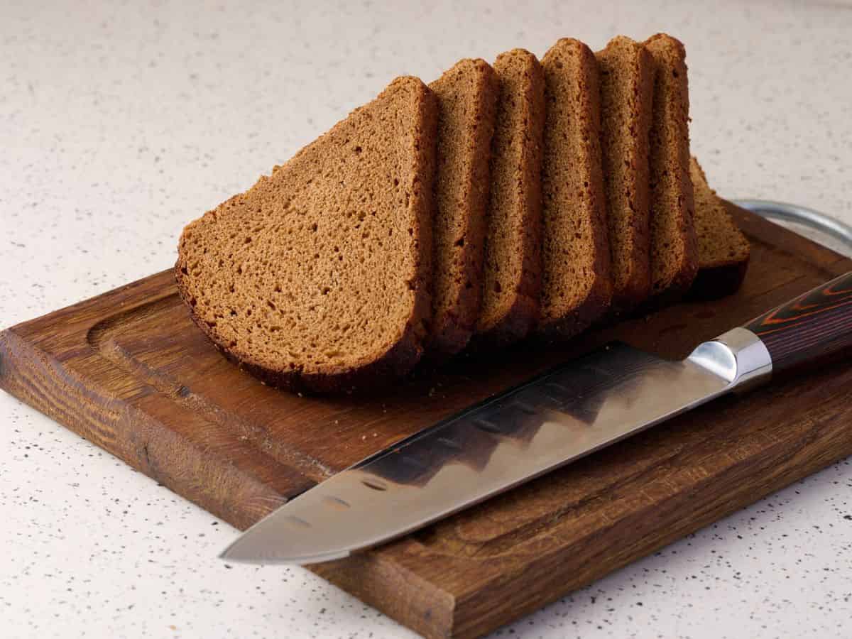 Slices of German rye bread on a cutting board with a knife.