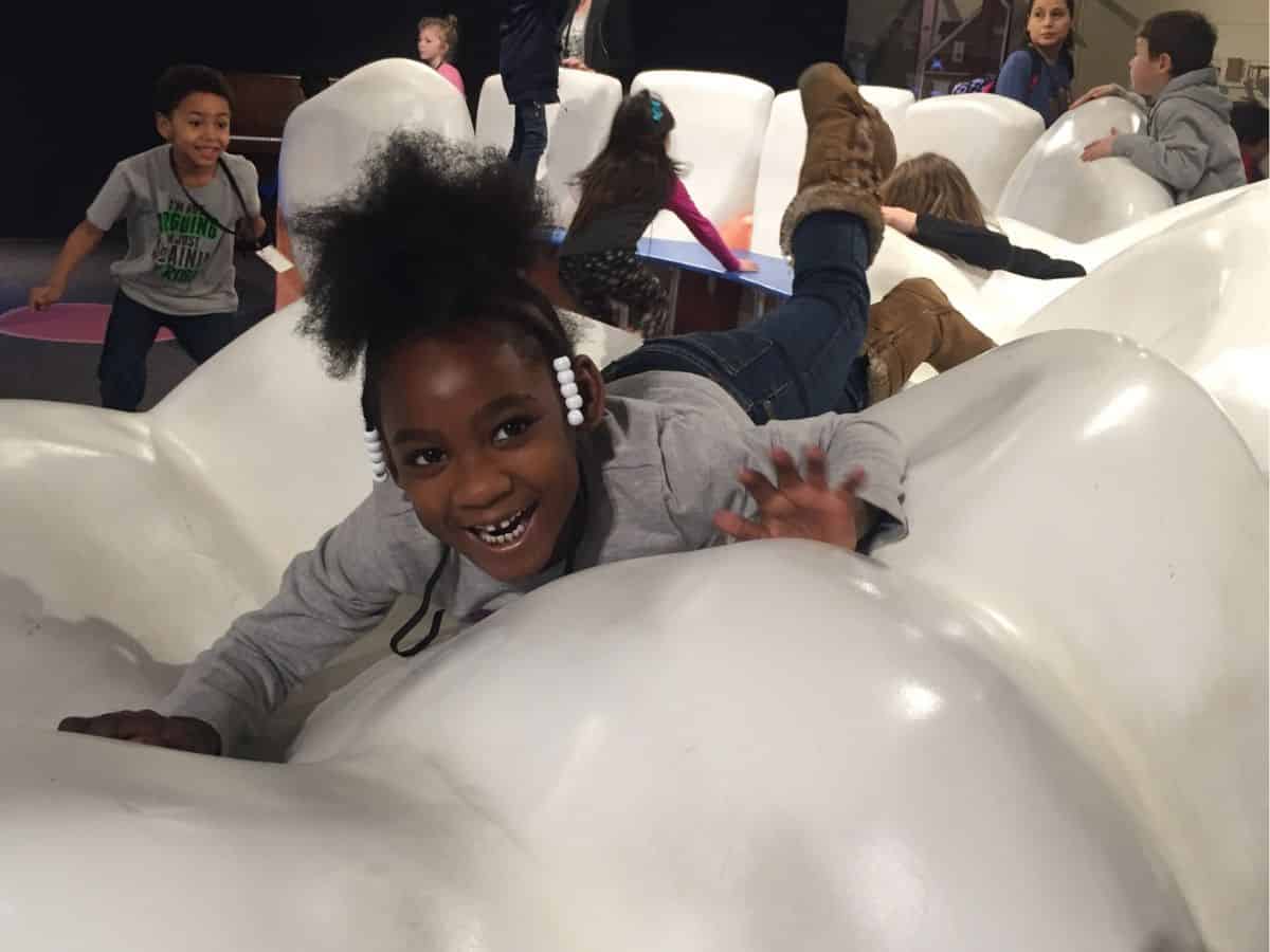 A young girl resting atop a colossal tooth at the Cincinnati Museum Center.