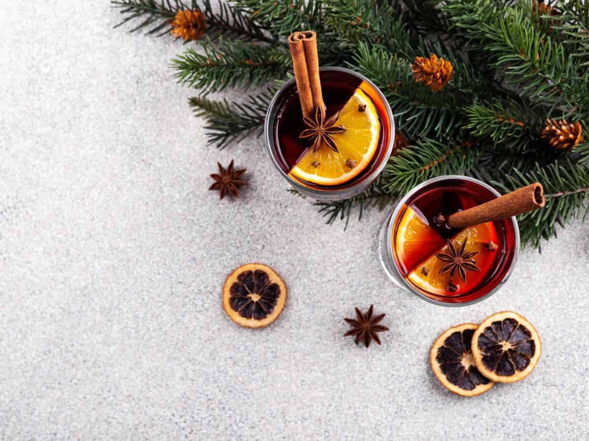 Two glasses of mulled wine with cinnamon sticks and fir branches.
