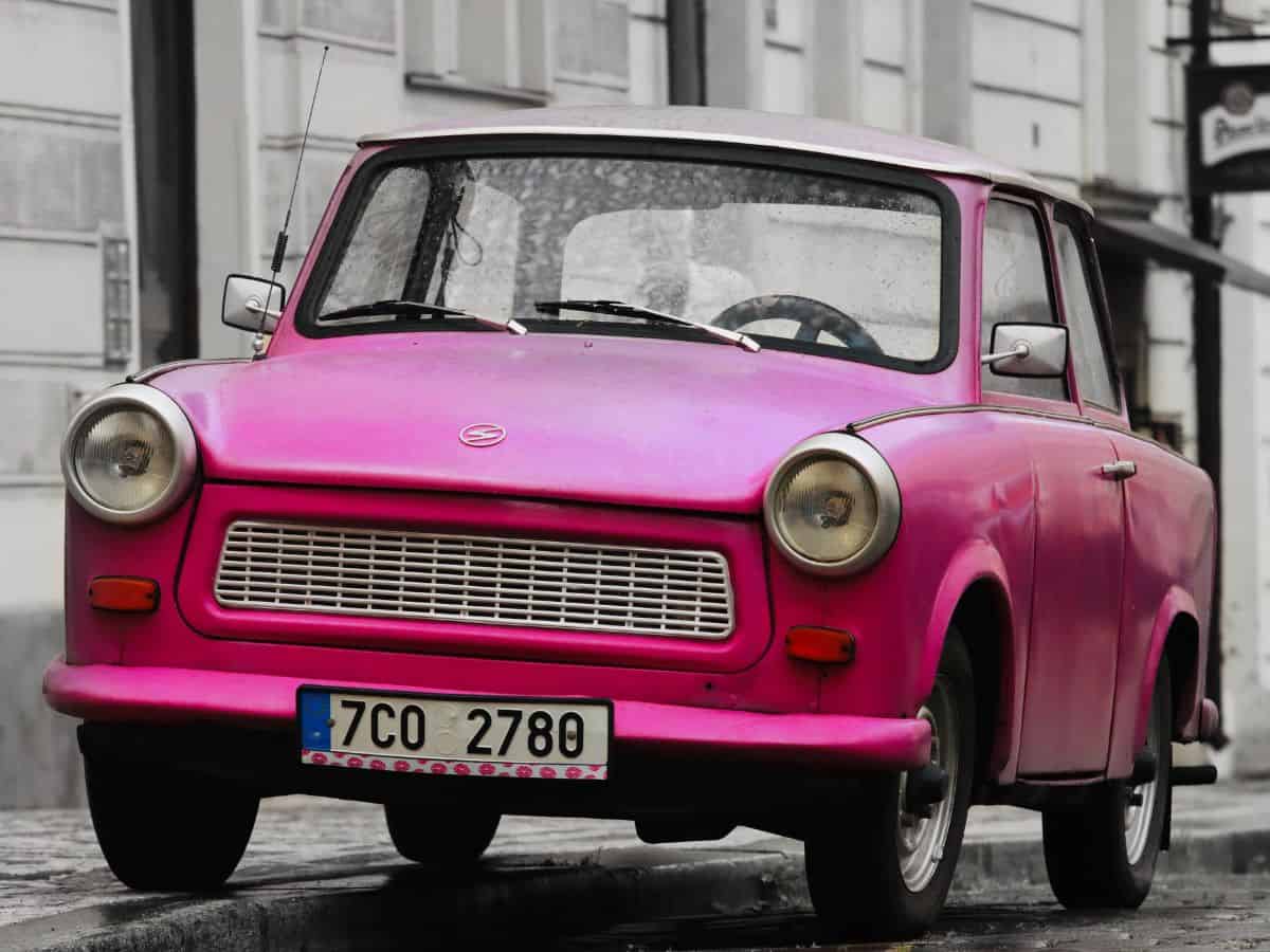 A vintage pink Trabant car parked on the street.