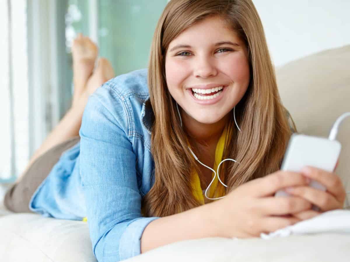 A young woman smiling while listening to music.