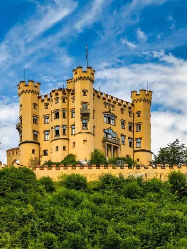 A yellow castle sits on top of a green hill.