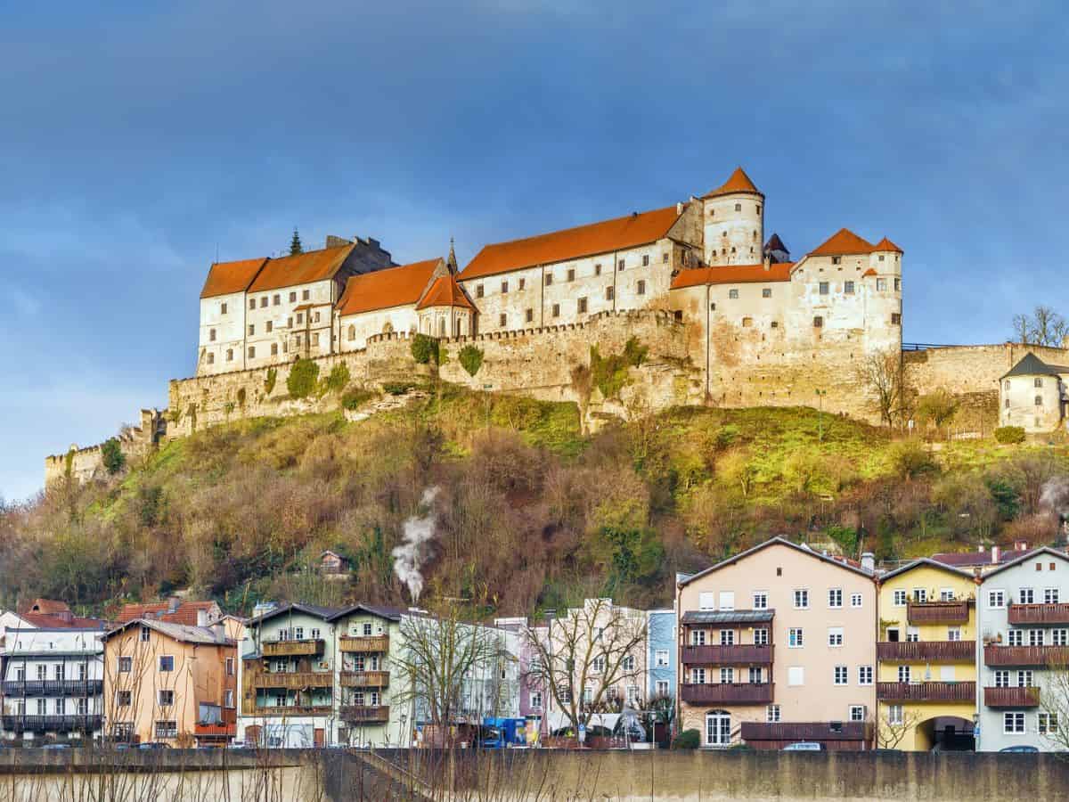 A German castle sits on top of a hill overlooking a river in Germany.
