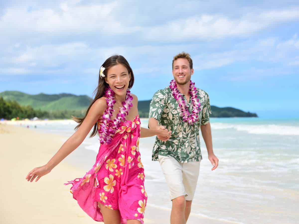 Hawaiian couple running on the beach while enjoying a luau.