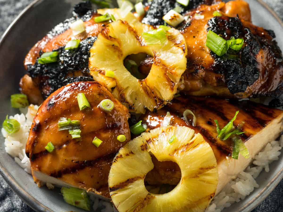A plate of huli huli chicken topped with grilled pineapple.