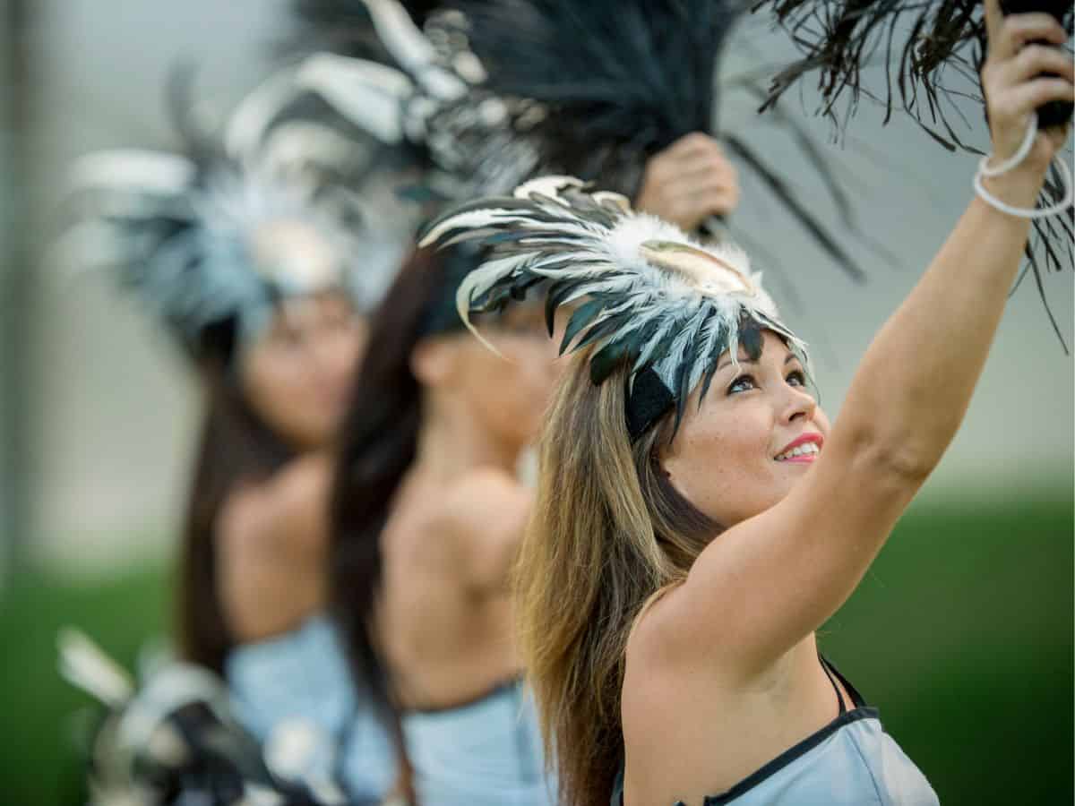 A group of dancers with feathers in their hair performing at a luau.