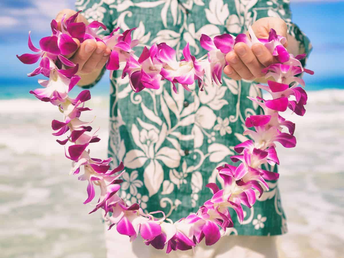 A man holding a heart shaped lei on a Hawaiian beach.