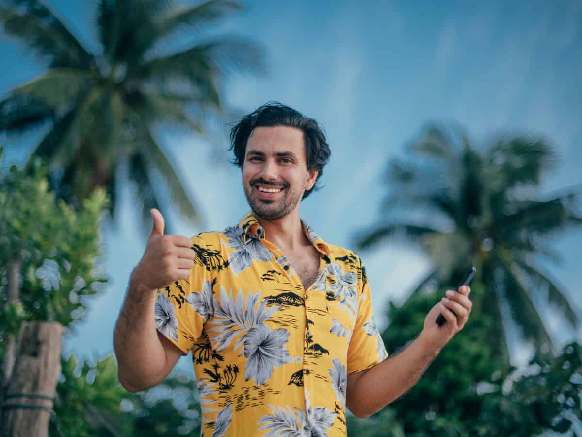 A man in a hawaiian shirt giving a thumbs up, showcasing the perfect attire for a luau.