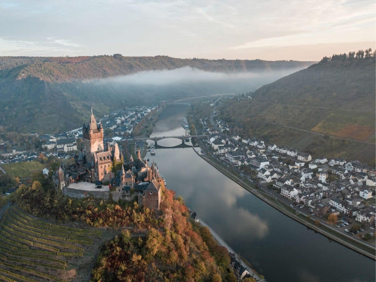 An aerial view of a German castle on a hill overlooking a river.