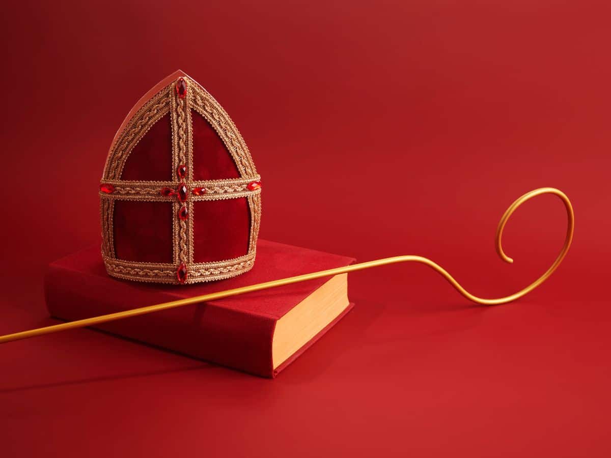 A Sinterklaas bishop's hat and a book on a red background.